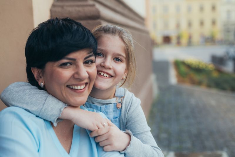 smiling mother and daughter outside taking picture together